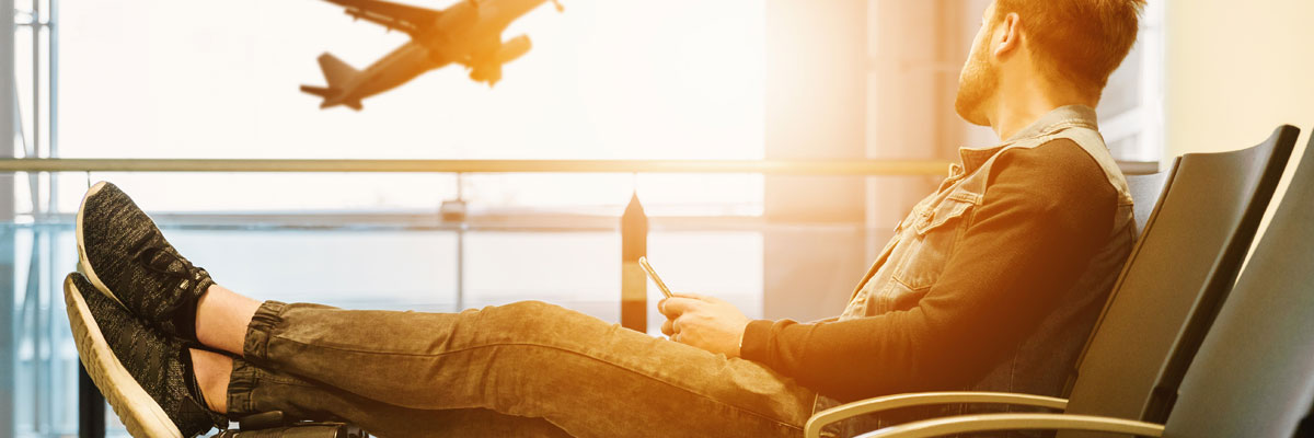 man sitting at airport lounge with plane outside window